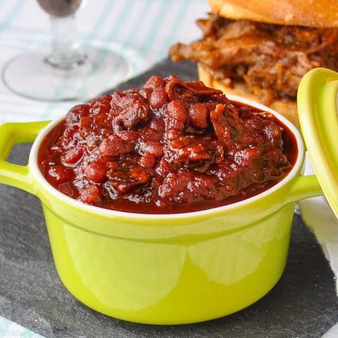 Old Fashioned Molasses and Bacon Baked Beans square cropped featured image of baked beans served in a green dish.