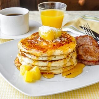 Pina Colada Pancakes on white plate with sausage patties