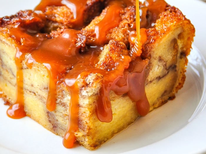 Close up of Cinnamon Roll Bread Pudding with caramel sauce being drizzled on top