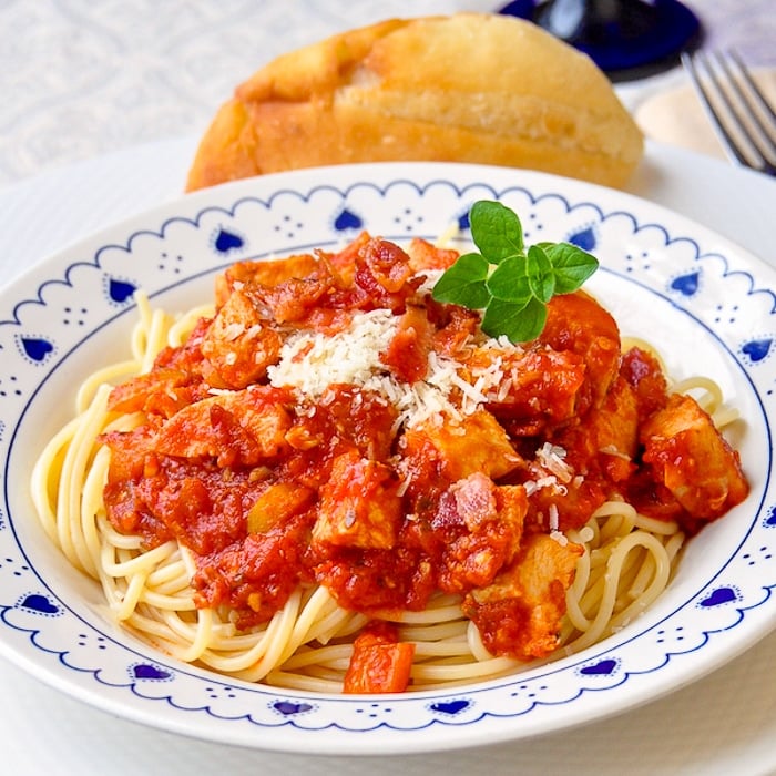 Leftover Chicken Spaghetti with Bacon in white bowl with bread roll