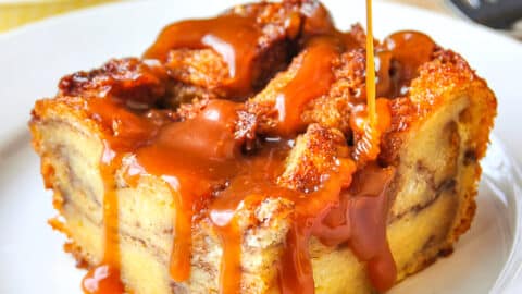 One serving of Cinnamon Roll Bread Pudding with caramel sauce on a white plate