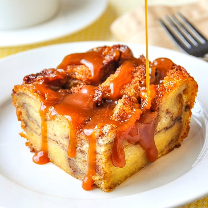One serving of Cinnamon Roll Bread Pudding with caramel sauce on a white plate
