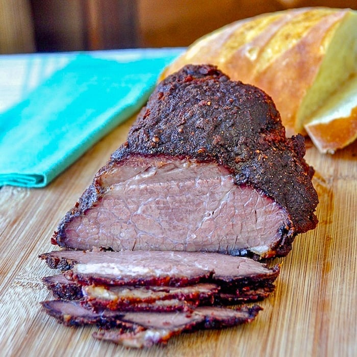 BBQ Beef Brisket shown being sliced on a wooden cutting board