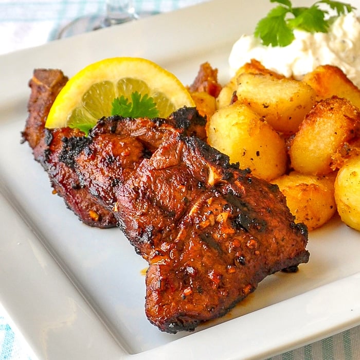 Garlic Balsamic Lamb Chops close up image of two lamb chops with roasted potatoes on a white plate