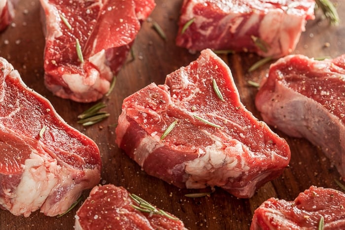 Raw lamb chops on a wooden cutting board