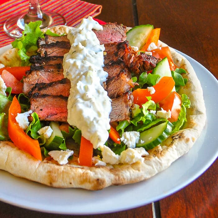 Soulaki Steak shown served with Greek salad on homemade flatbread.