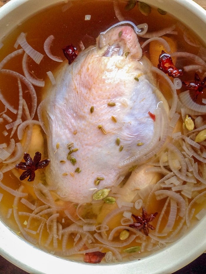 Asian Spice Brined Roast Chicken soaking in the brine mixture