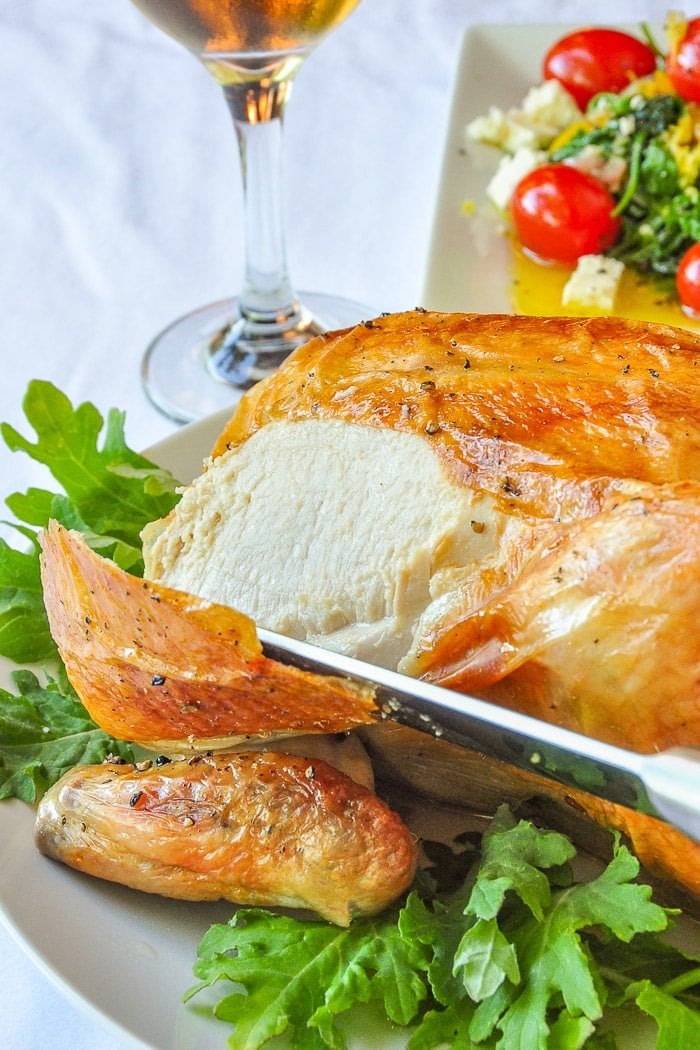 Asian Spice Brined Roast Chicken soaking in the brine mixture with wine and salad on the side