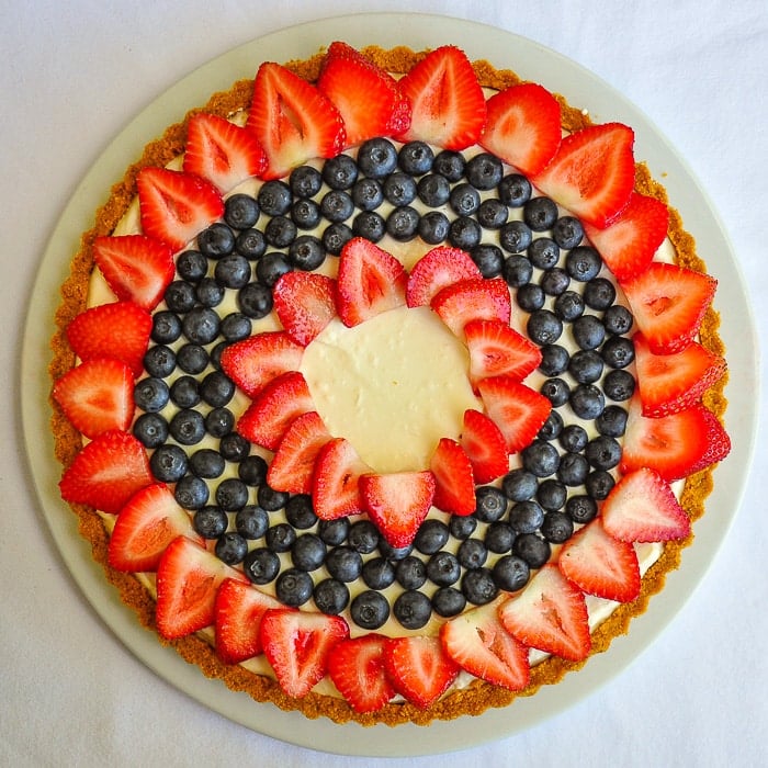 Photo of an uncut No Bake White Chocolate Cheesecake Tart on a white serving plate