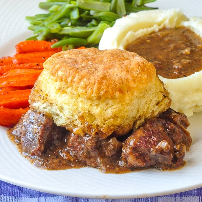 Braised Beef Pot Pie with Biscuit Topping close up photo of single serving on a white plate
