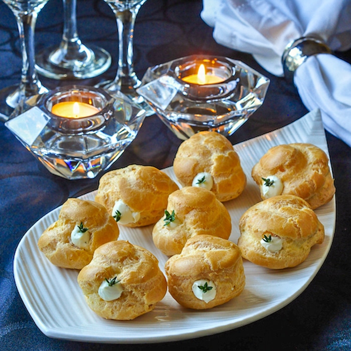 Garlic Thyme Cheese Puffs shown with candles on a white serving platter.