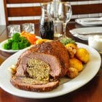 Smoked Paprika Lamb with Summer Savory Stuffing Square cropped featured image of carved lamb with side dishes