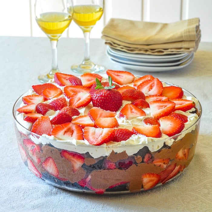 Chocolate Mousse Strawberry Trifle wide shot photo of full trifle bowl with wine glasses in background