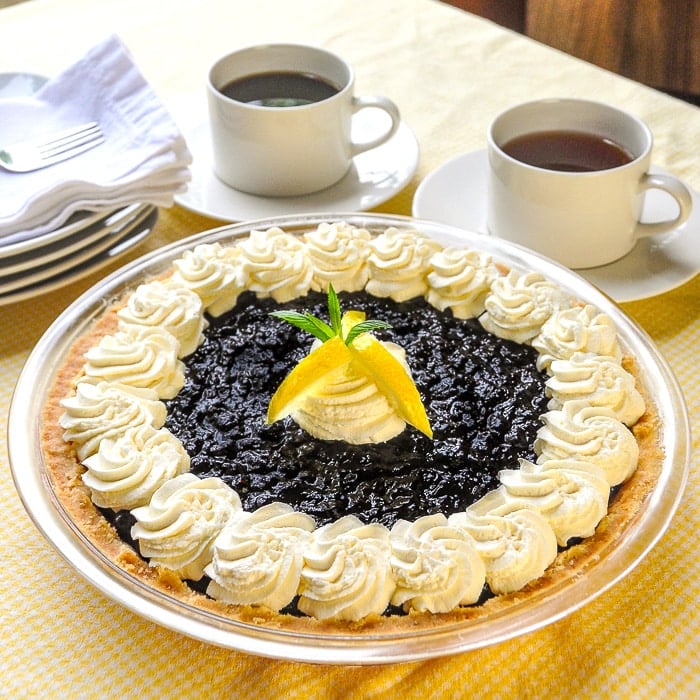 Photo of completed Lemon Blueberry Cheesecake Pie with coffee in the background