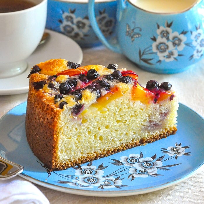 Blueberry Peach Sour Cream Cake close up photo of one single slice on a blue plate