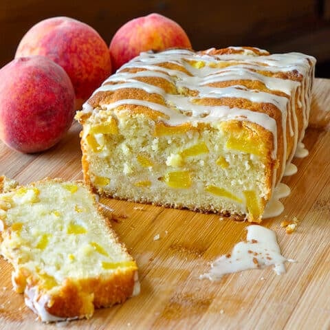 Peach Cake with Vanilla Glaze on a wooden cutting board