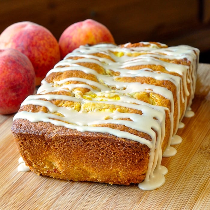 Peach Cake with Vanilla Glaze uncut with peaches in the background