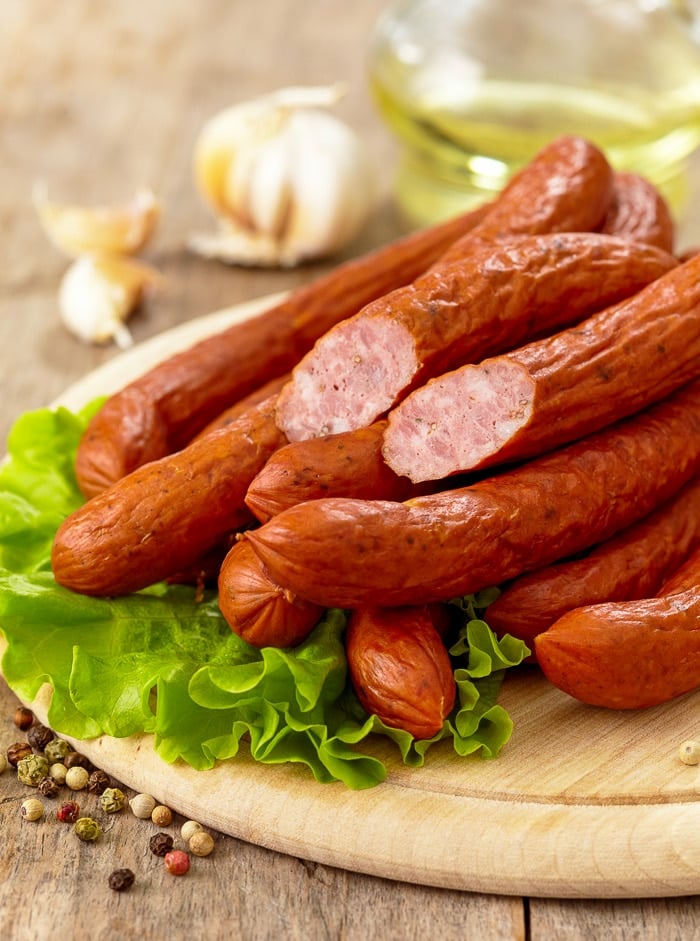 Stock photo of smoked sausages on a wooden cutting board.