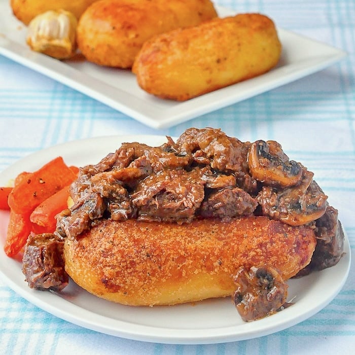 Guiness Braised Beef and Roasted Potatoes close up image of single serving on a white plate