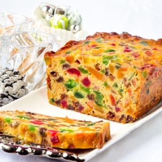 Apricot Fruitcake shown on a white background with candles in background