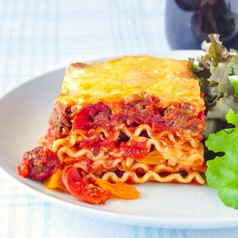 Pizza Lasagna serving on white plate with green salad