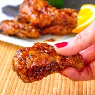 Close up photo of Crispy Orange Ginger Wings held between fingers