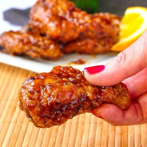 Close up photo of Crispy Orange Ginger Wings held between fingers