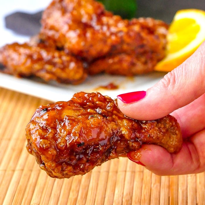 Close up photo of Crispy Orange Ginger Wings held between fingers