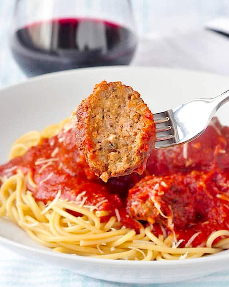 The Best Spaghetti and Meatballs close up photo of a meatball with a bite taken out.