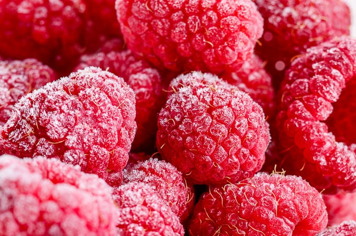 Red frozen raspberries background closeup photo