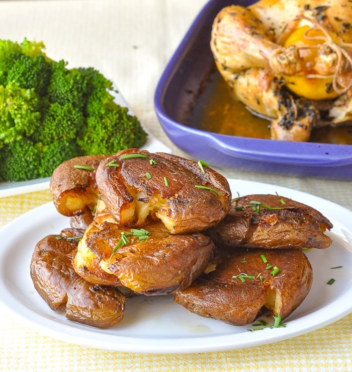 Smash Roasted Potatoes pictured with roast chicken and steamed broccoli in the background