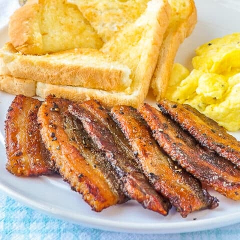 Homemade Bacon with eggs and toast on white plate