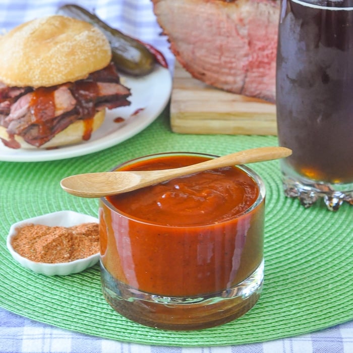 Smoky Spice Honey Barbecue Sauce in a clear glass container with small wooden spoon