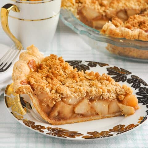 Deep Dish Apple Crumble Pie featured photo of a slice of cake on a white and gold plate