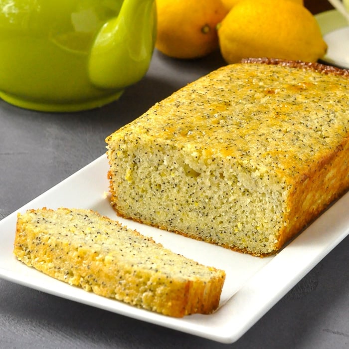 Lemon Poppy Seed Loaf Cake close up photo of sliced cake on a white platter