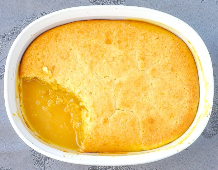 Lemon pudding cake with one serving removed to show lemon sauce at the bottom