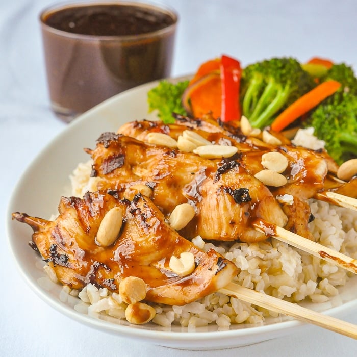 Peanut Butter Sriracha Chicken Satay served on a bed of rice with steamed vegetables