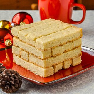 Scottish Shortbread stacked on a red plate surrounded by christmas decorations