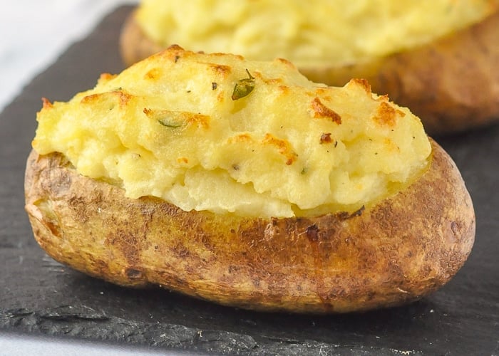 Twice Baked Potatoes with Smoked Cheddar & Thyme close up image of one potato on slate serving platter