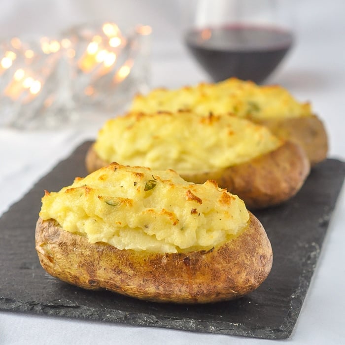 Twice Baked Potatoes with Smoked Cheddar & Thyme on a slate serving platter with wine and candles in background