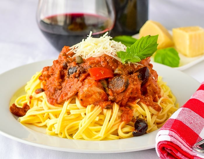 Chicken Amatriciana photo of one serving with a red checkered napkin and basil garnish