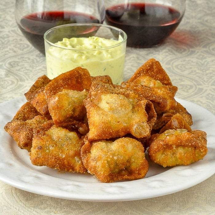 Curry Chicken Stuffed Wontons on a white plate with dip