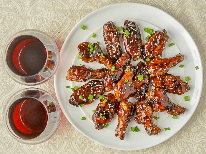 Glazed Teriyaki Chicken Wings shown with 2 glasses of red wine