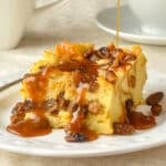 Close up photo of one serving of Rum Raisin Bread Pudding with sauce being poured on