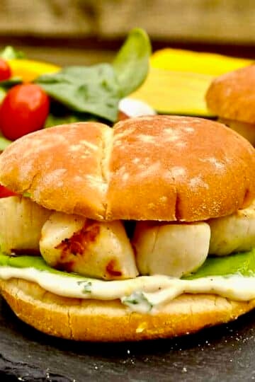 Grilled Scallops Burger with Lemon Basil Mayo shown with salad in thr background for featured image.