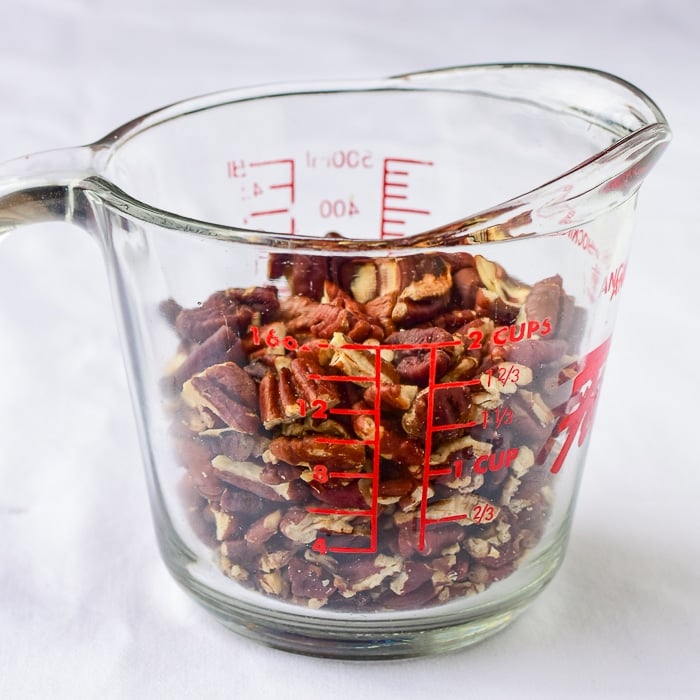 Pecan pieces in a clear glass measuring cup