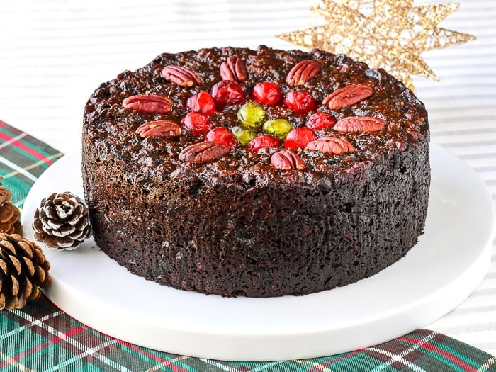 wide shot photo of whole uncut cake surrounded by christmas decorations on a Newfoundland tartan table runner