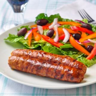 Homemade Chorizo Sausage shown with salad on a white plate