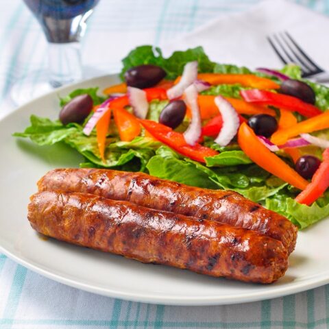 Homemade Chorizo Sausage shown with salad on a white plate