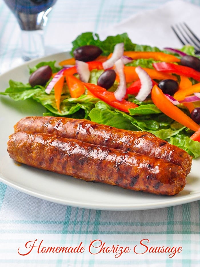 Homemade Chorizo Sausage shown with salad on a white plate with title text added for Pinterest